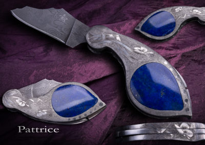 patt-art-celtic coutelier, forgeron, graveur à Val d'Anast en Ille-et-Vilaine. L'Akène, système à pompe arrière, lame en damas inox, corps en 316L, gravures en taille douce sur grisure, incrustations de lapis lazuli, 10cm ouvert.